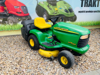  zahradni traktor john deere zelene barvy s velkymi koly pred plachtou traktory